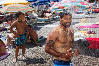 a man standing under a shower on a beach