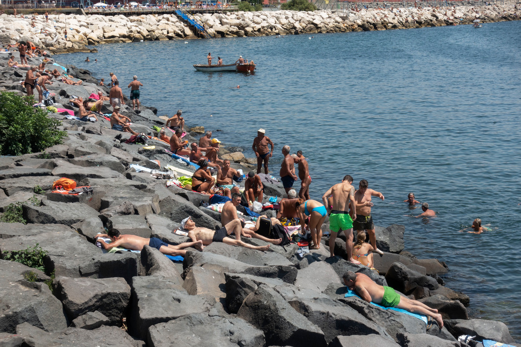 a large group of people are on the rocks by the water