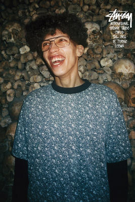 a man wearing glasses standing in front of a pile of rocks