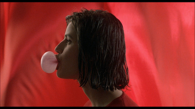 a woman blowing a bubble with a red background