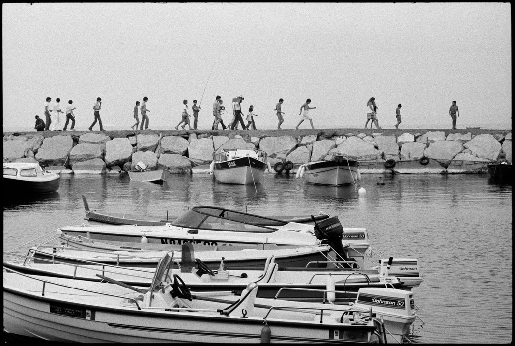 a group of people walking across a bridge over water