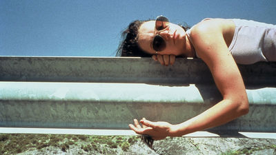 a woman wearing sunglasses leaning on a rail