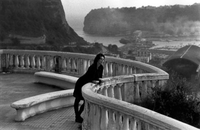 a woman standing on a balcony next to a body of water