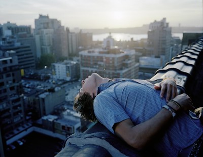 a man laying on top of a roof next to a city