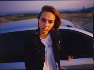 a woman standing in front of a white car