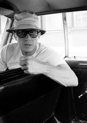 a man wearing a hat and sunglasses sitting in a car