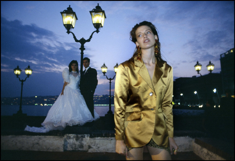 a woman in a gold suit standing next to a man in a black suit