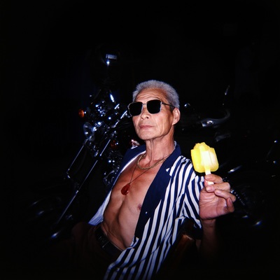 a shirtless man holding a yellow piece of food