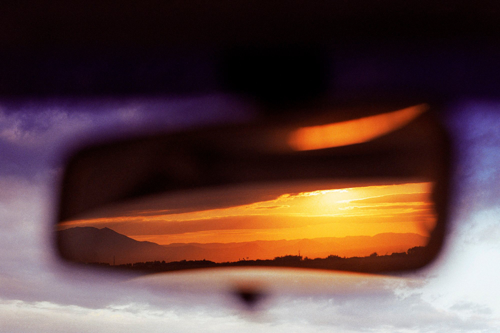 a sunset seen through a rear view mirror