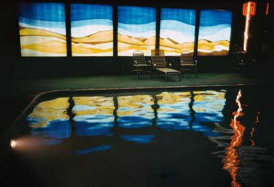 a chair sitting in front of a large window next to a swimming pool