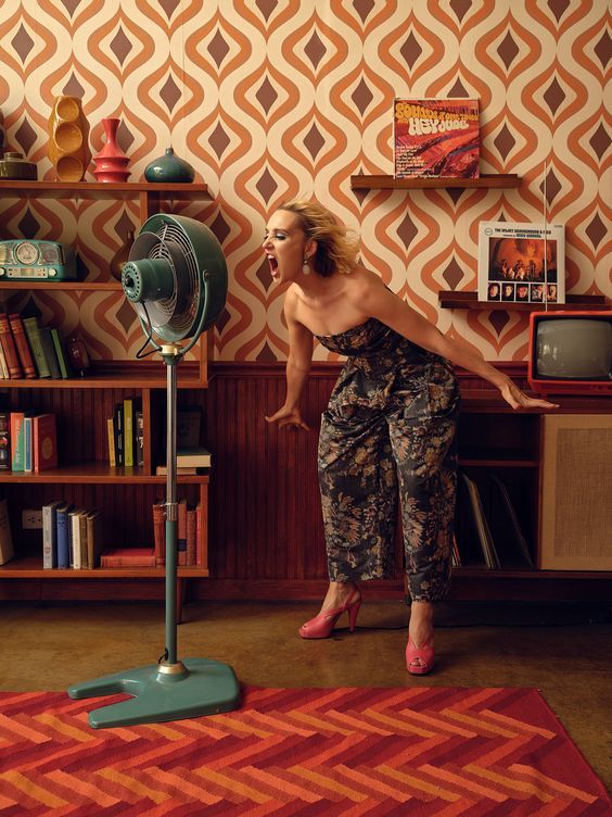 a woman standing next to a fan in a room