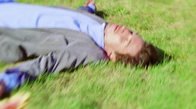 a man laying in the grass with his eyes closed