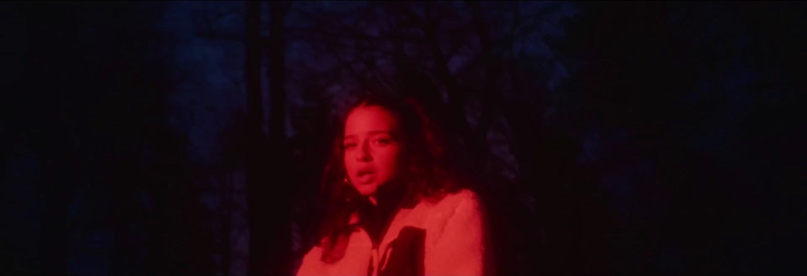 a woman standing in the dark with a red light on her face