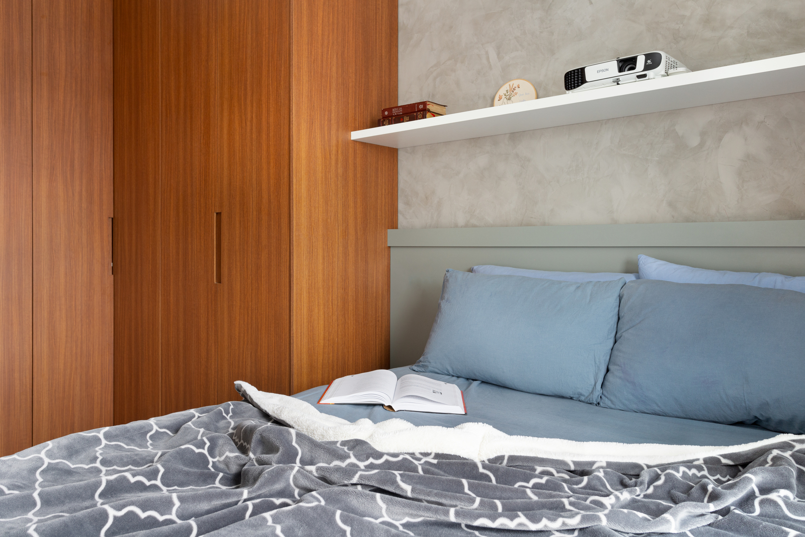 a bed with a blue comforter and a book on top of it