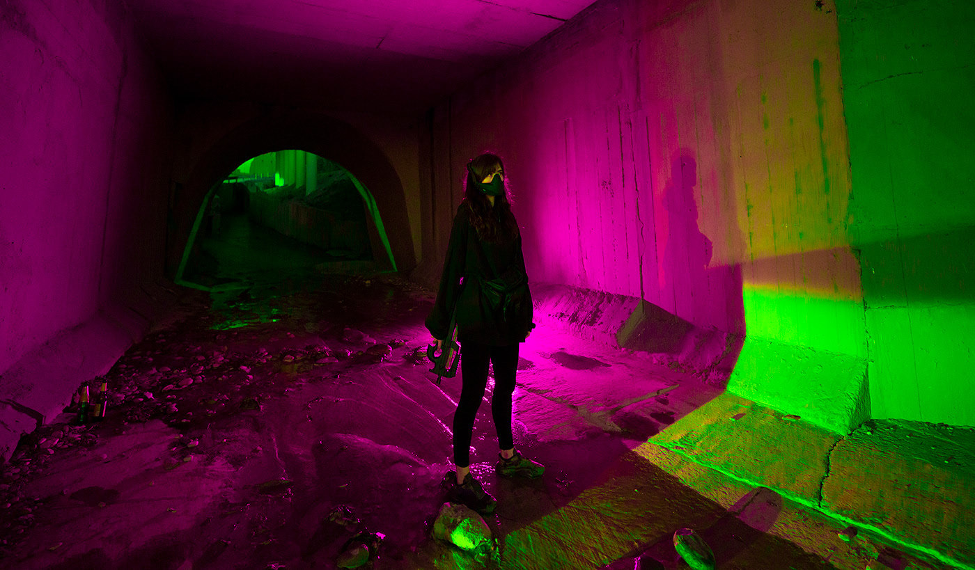 a woman standing in a dark tunnel with neon lights