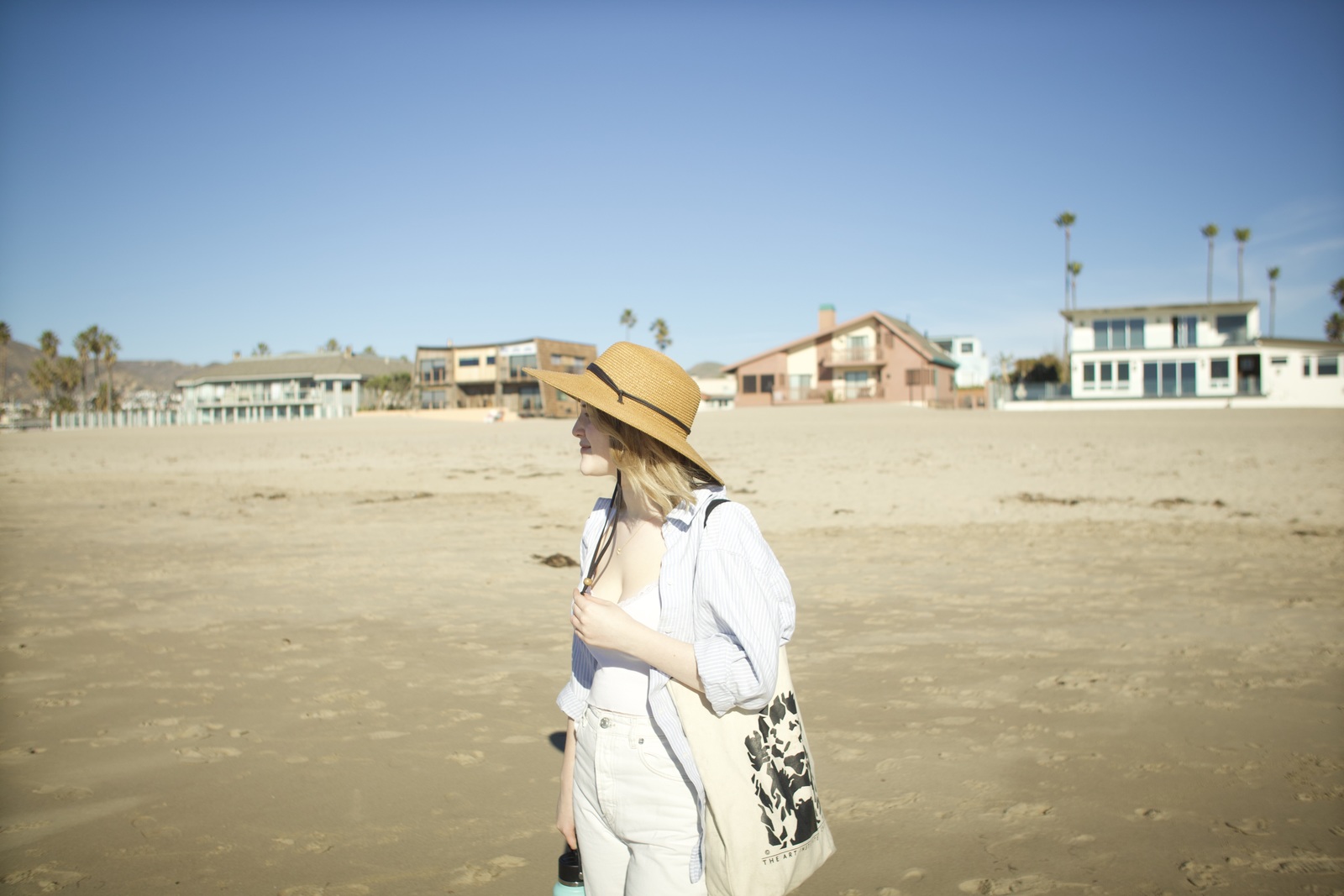 a woman in a hat is walking on the beach