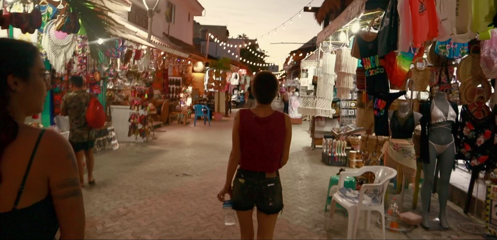 a woman walking down a street next to shops