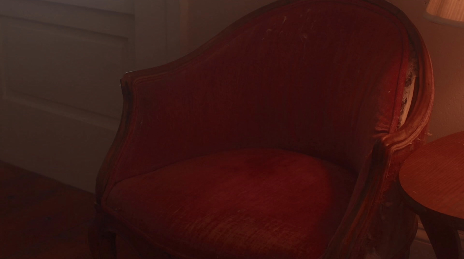 a red chair next to a table with a lamp on it