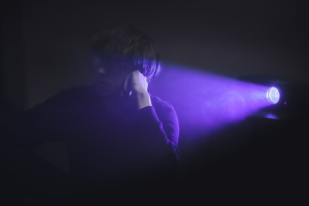 a person standing in front of a purple light