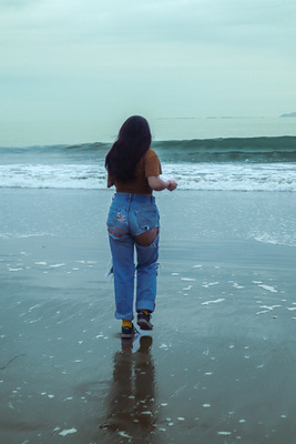 a woman standing on top of a beach next to the ocean