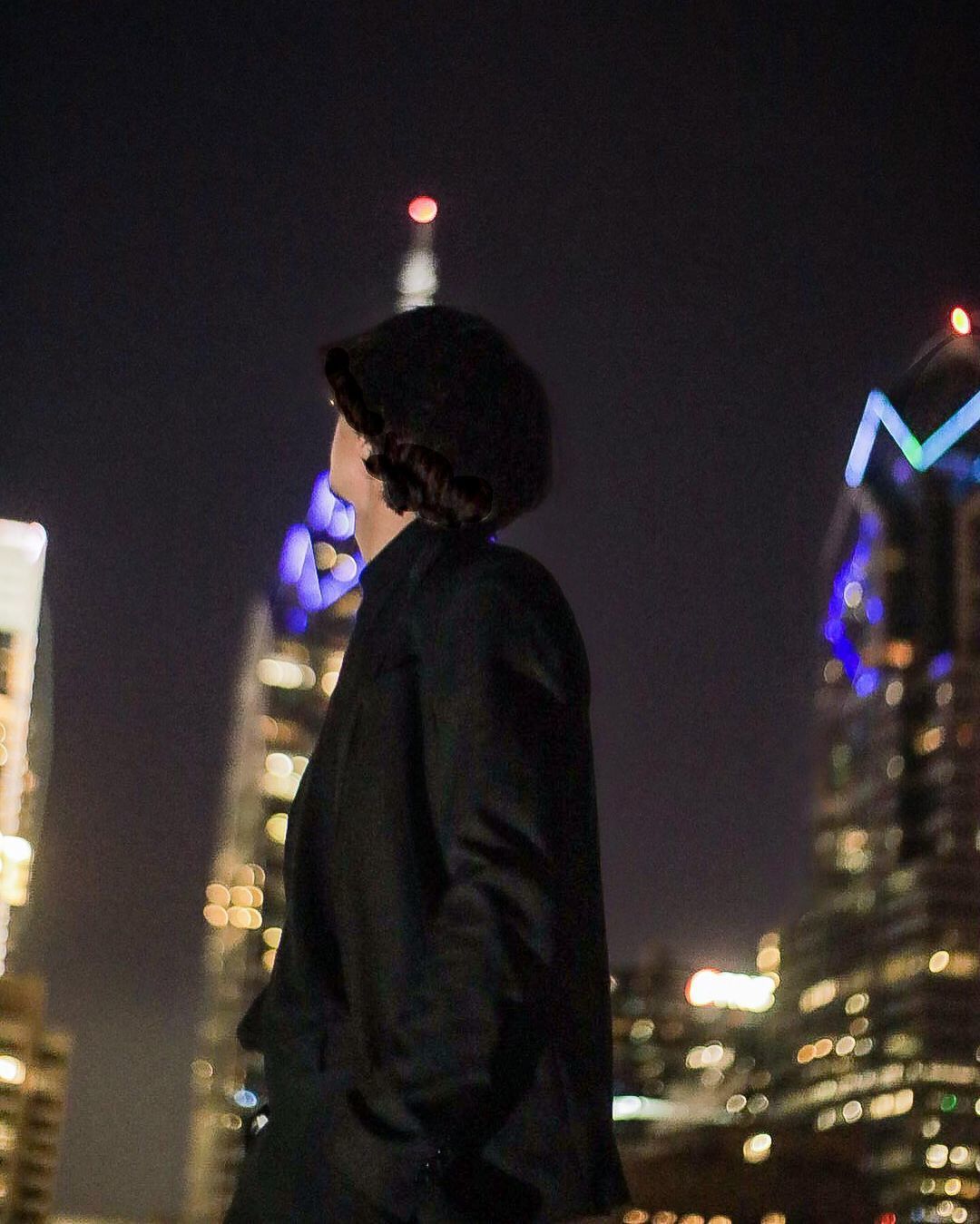 a man standing in front of a city skyline at night