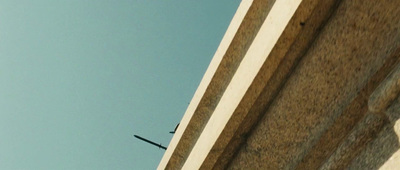 an airplane flying over a building with a sky background