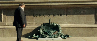 a man in a suit standing in front of a monument