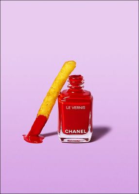 a bottle of chanel nail polish next to a yellow stick