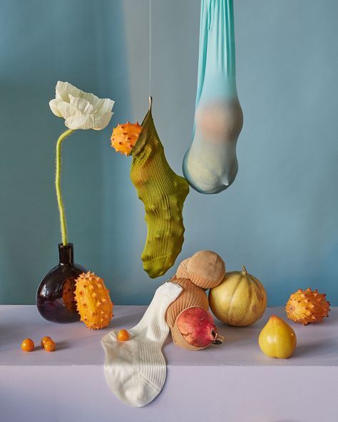 a table topped with a vase filled with fruit and vegetables