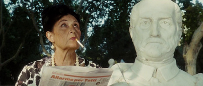 a woman standing next to a statue with a cigarette in her mouth