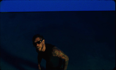 a man with tattoos and sunglasses standing in the dark