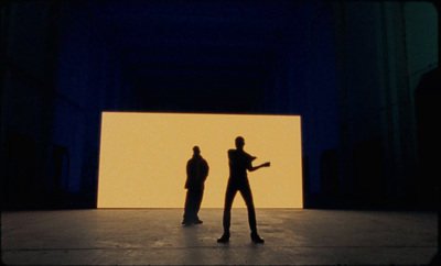 two people standing in front of a large screen