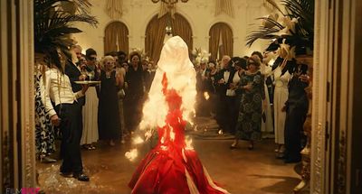 a group of people standing around a woman in a red dress