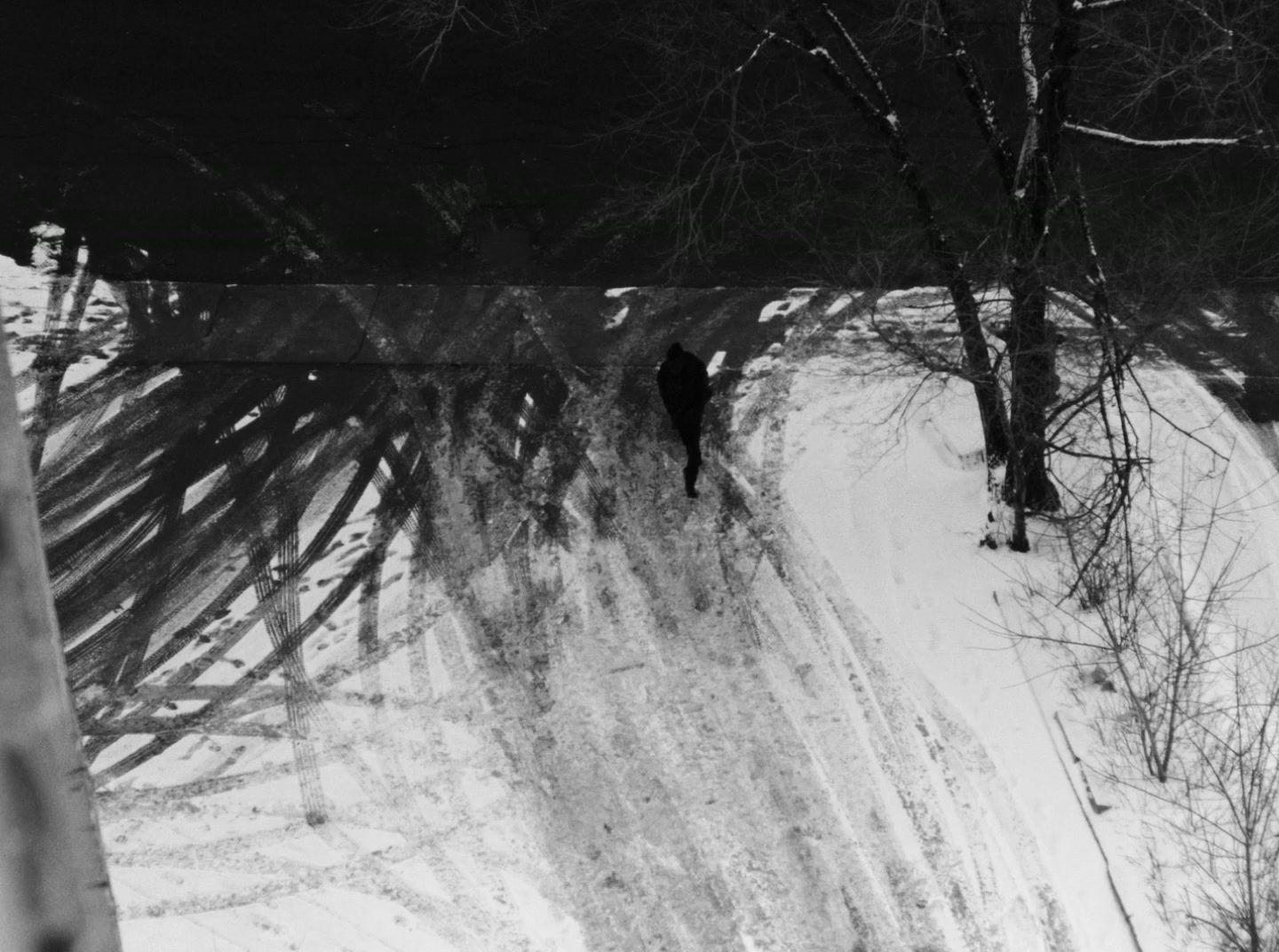 a black and white photo of a person walking in the snow