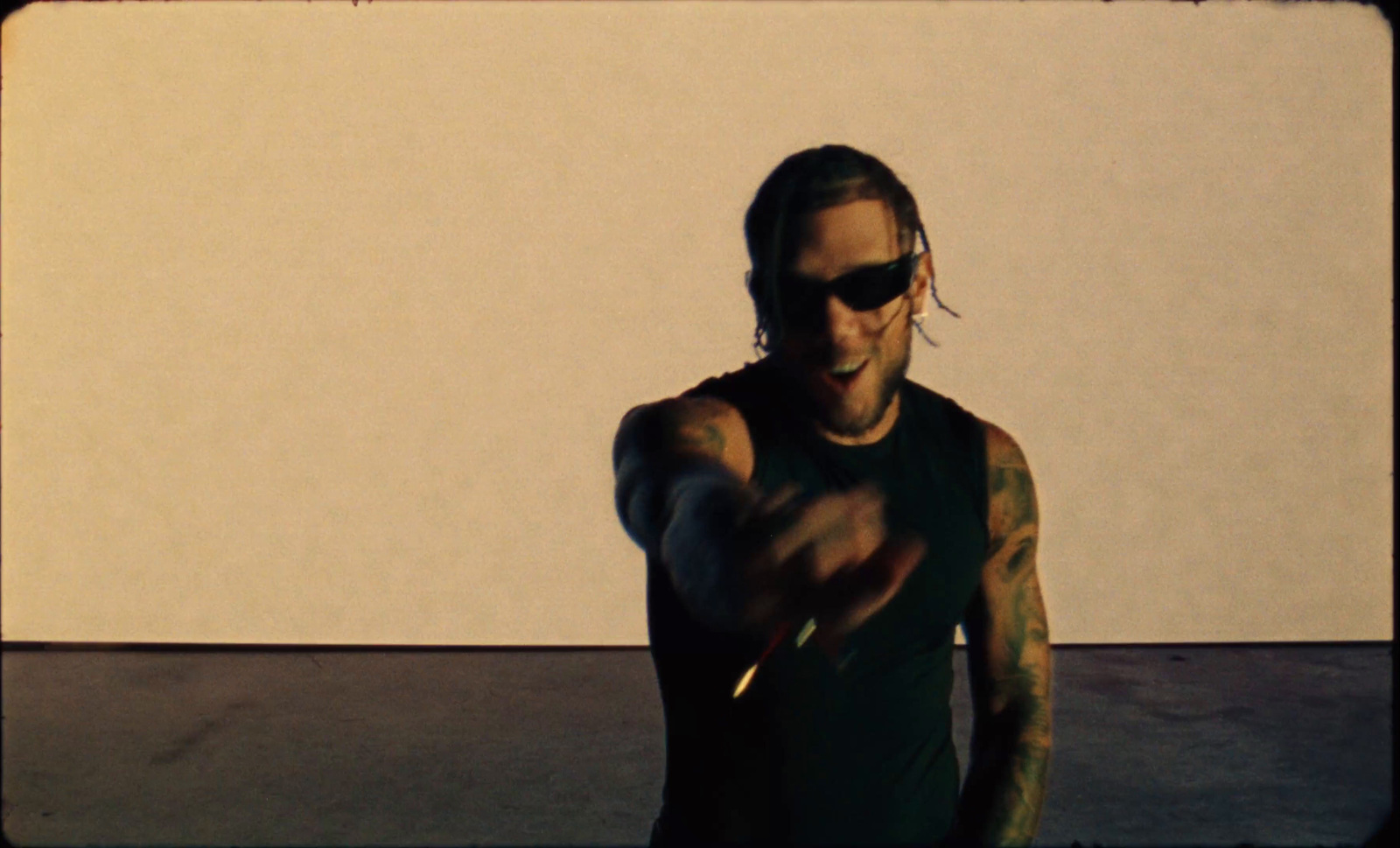 a man with tattoos and sunglasses pointing at something