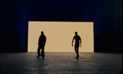 a couple of men standing in front of a white wall