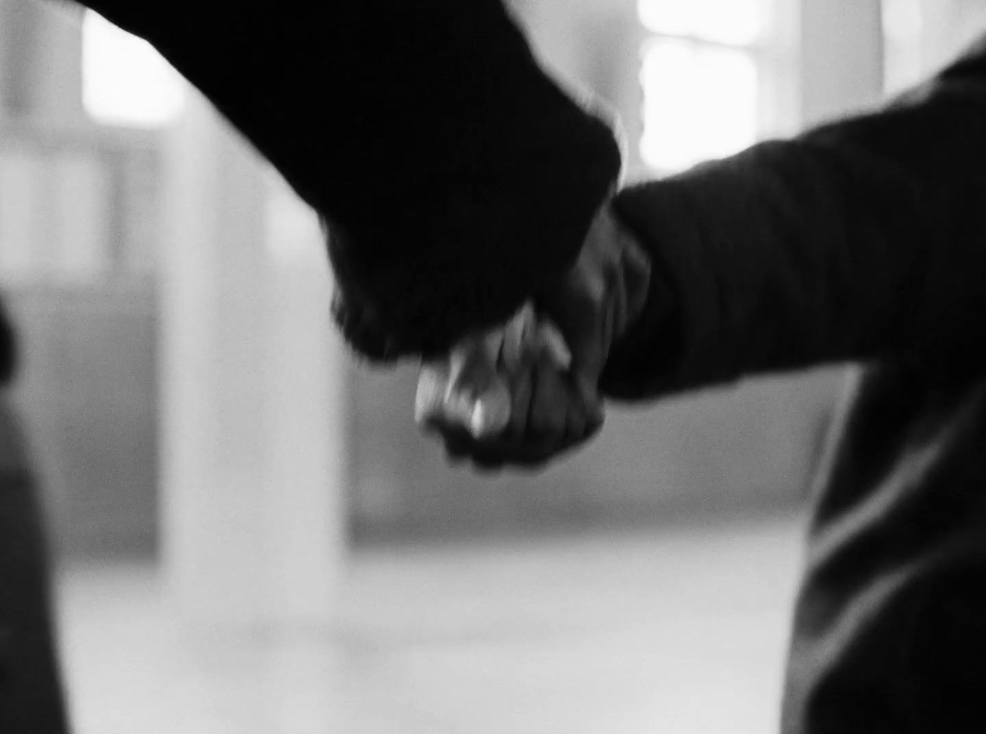 a black and white photo of two people holding hands