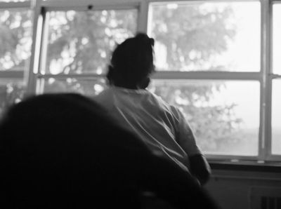 a person sitting in a chair looking out a window