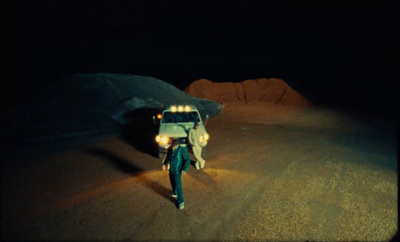 a person walking down a dirt road at night