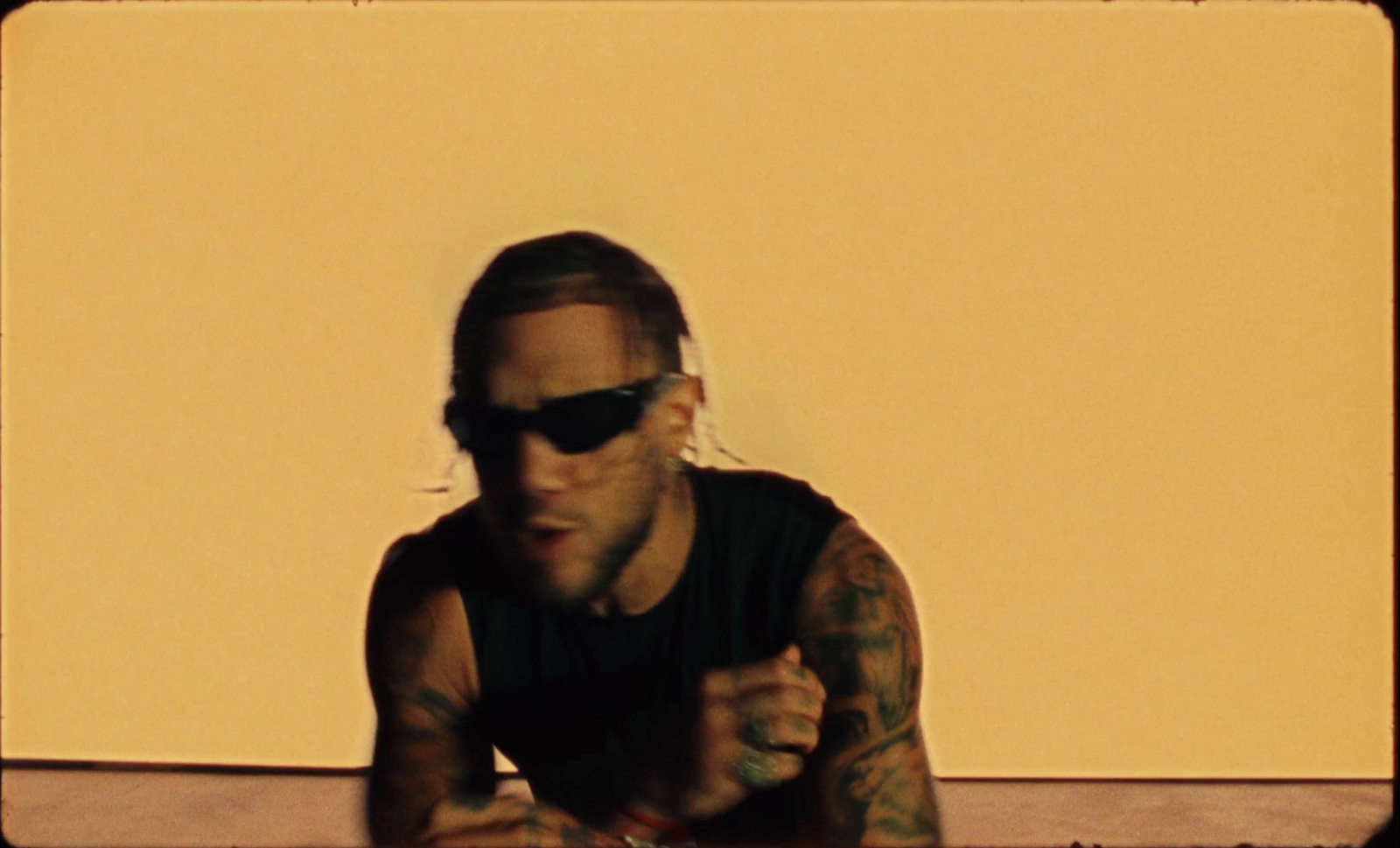 a man with tattoos and sunglasses sitting at a table