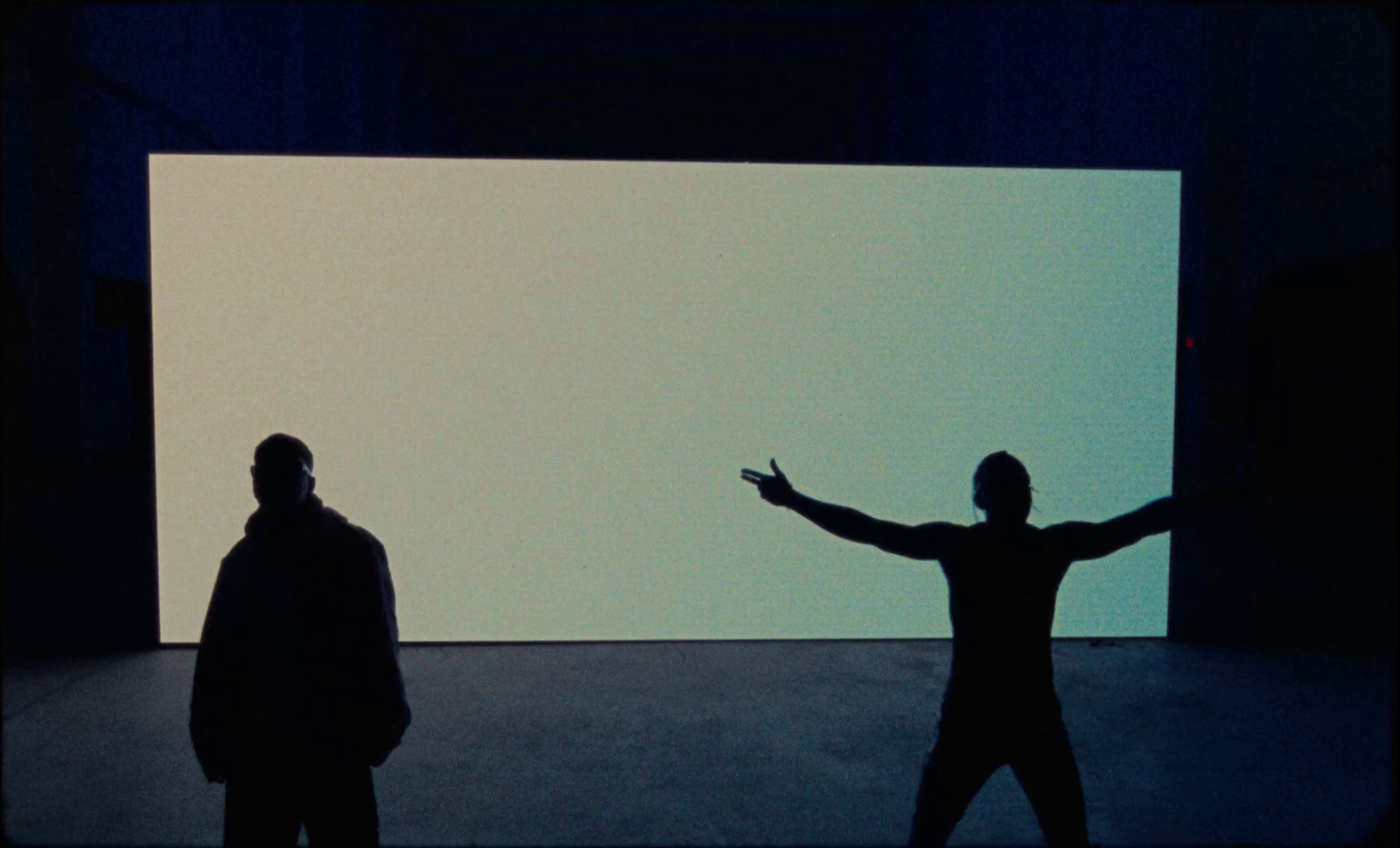 two people standing in front of a large screen