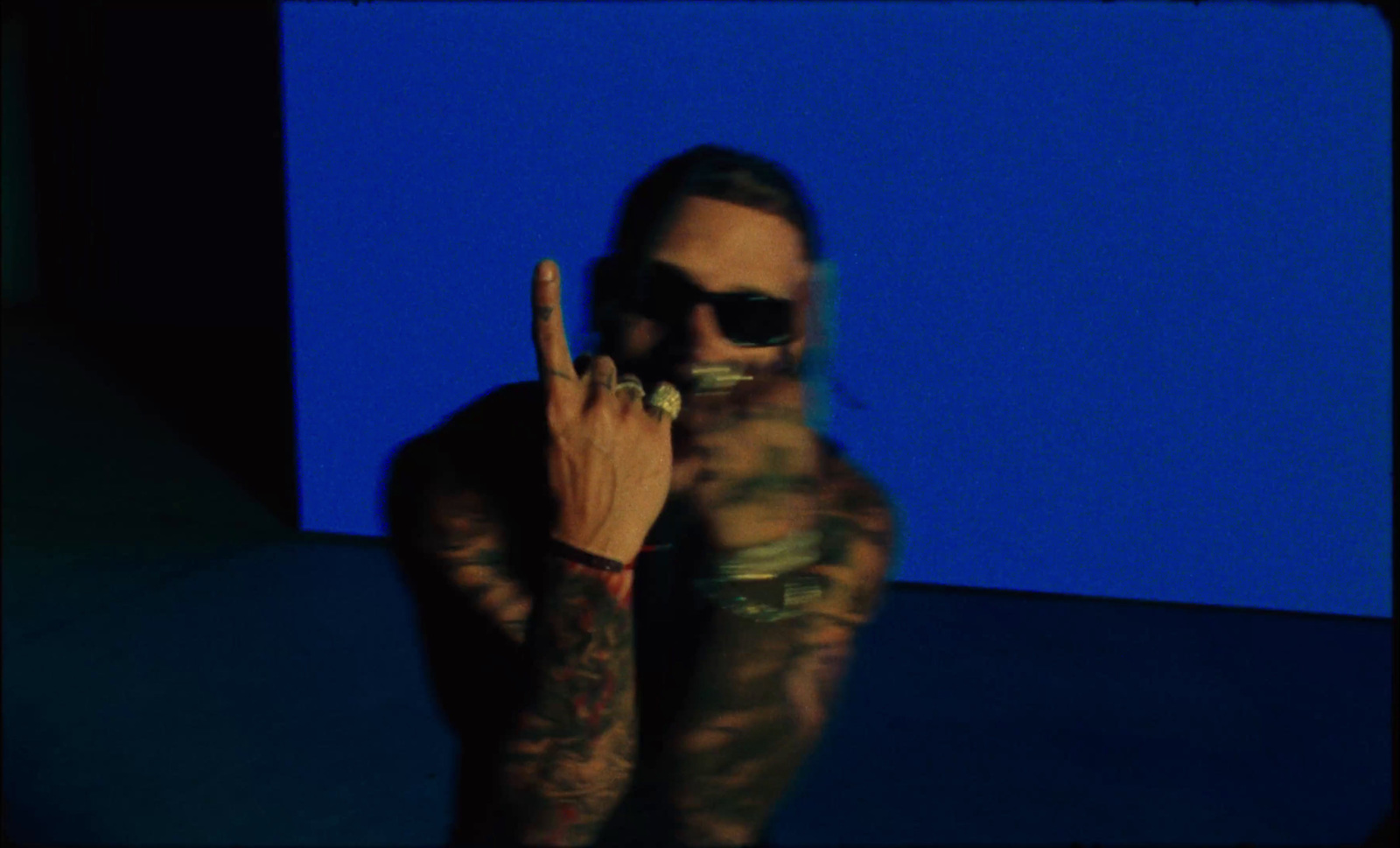 a man with tattoos and sunglasses making a peace sign