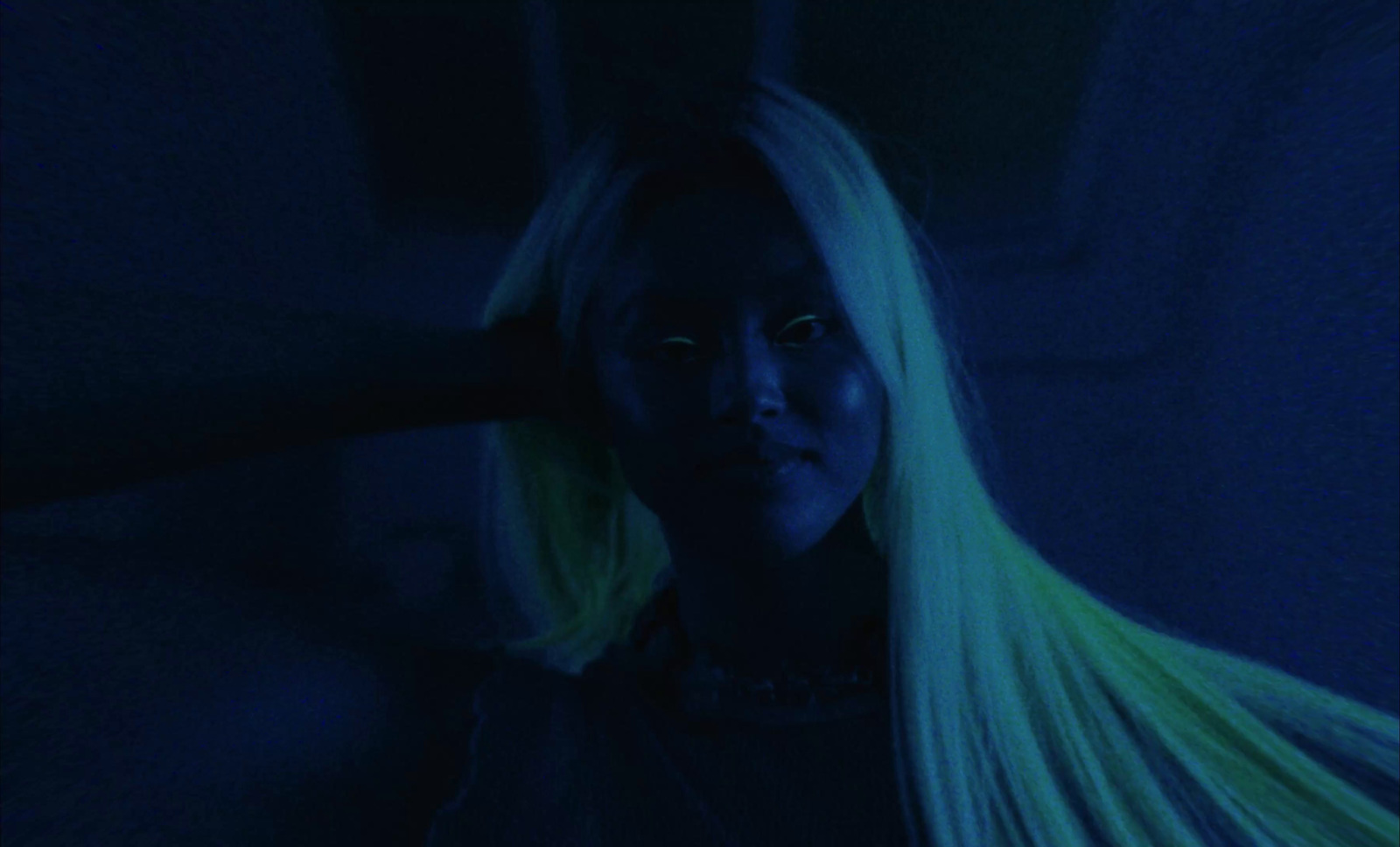 a woman with long blonde hair in a dark room