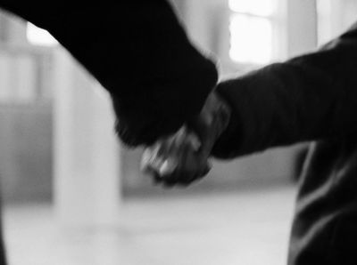 a black and white photo of two people holding hands