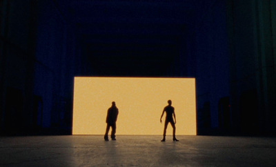 two people standing in front of a large screen