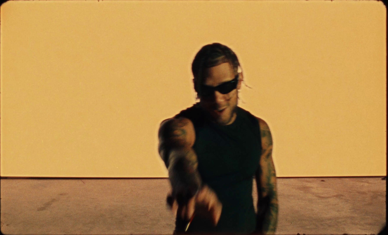 a man with tattoos and sunglasses holding a skateboard