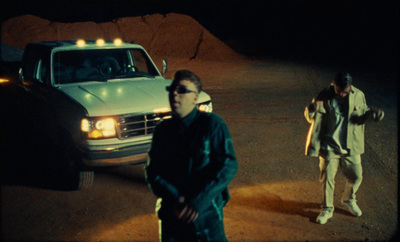 two men standing in front of a car in a parking lot