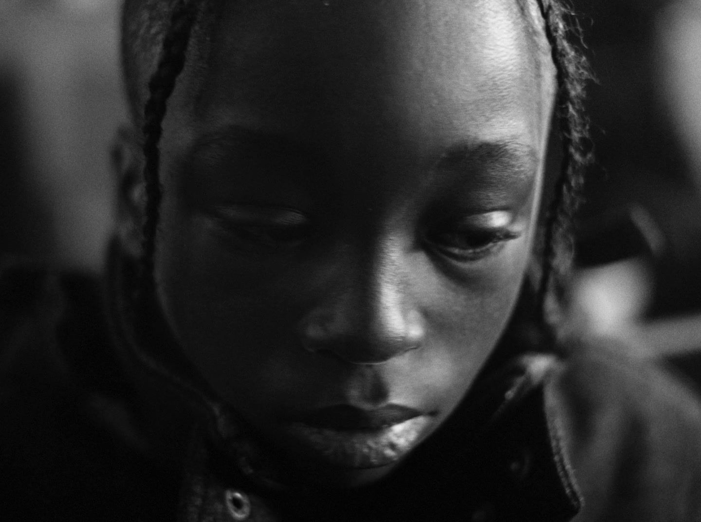 a woman with braids is looking down at her cell phone