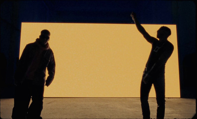 two men standing in front of a large screen