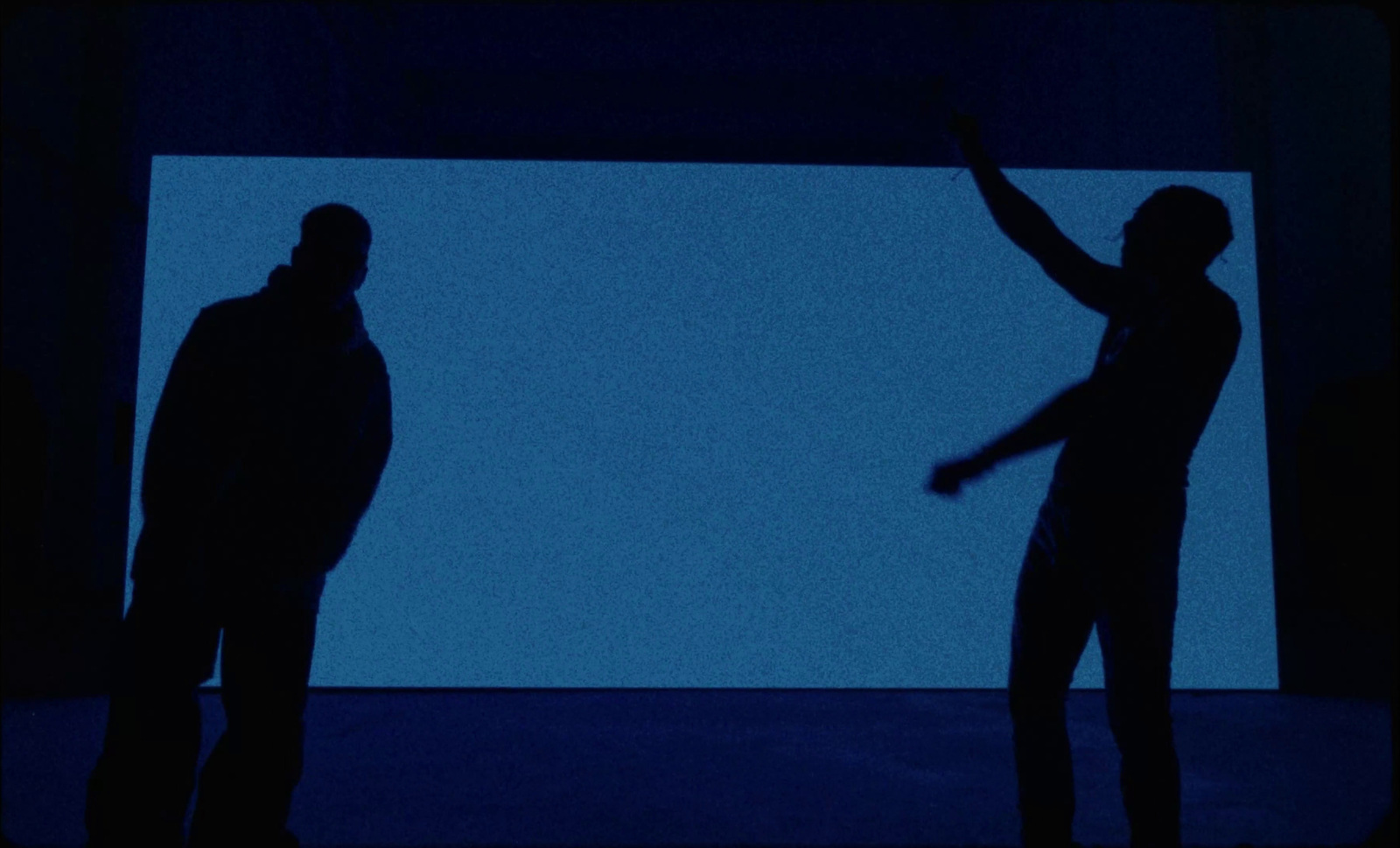 two people standing in front of a large screen